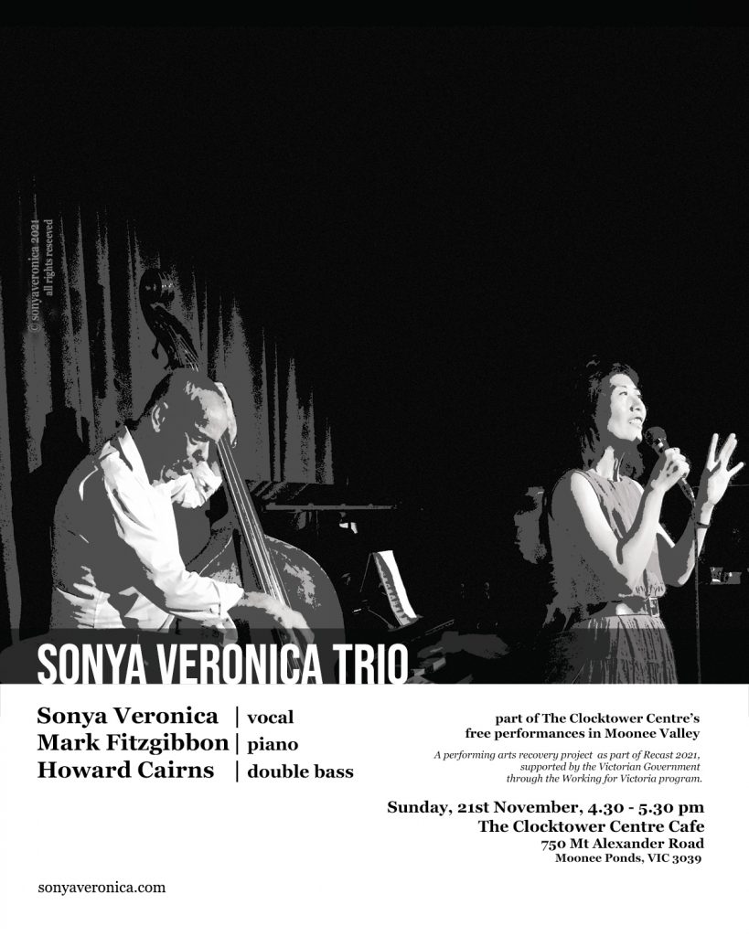 The picture depicts a trio playing music on stage. The trio comprises of a double bass player, a pianist and a singer. 
